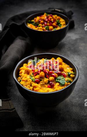 Studio shot of two bowls of vegan curry with red lentils, sweet potatoes, spinach, roasted turmeric chick-peas, pomegranate seeds and cilantro Stock Photo