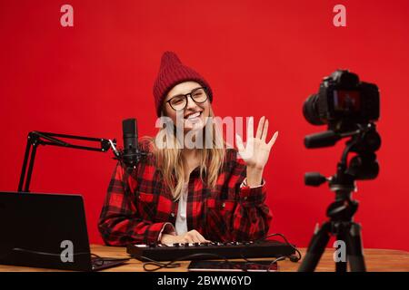 Young woman sitting at the table she working as a radio dj she smiling and waving to the camera at studio Stock Photo