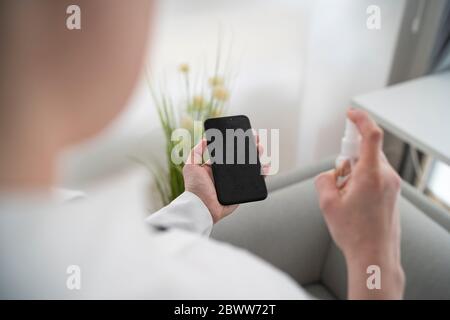 Close-up of woman disinfecting cell phone Stock Photo