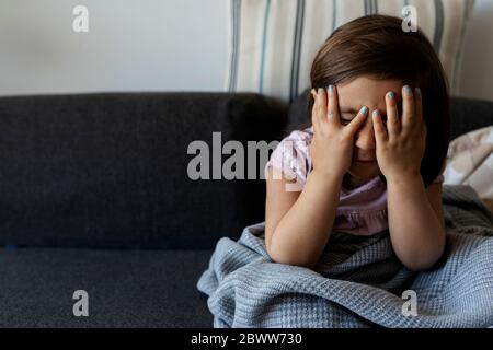 Portrait of girl sitting on couch with obscured face at home Stock Photo