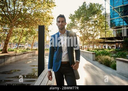 Smiling young businessman walking to work in the city Stock Photo