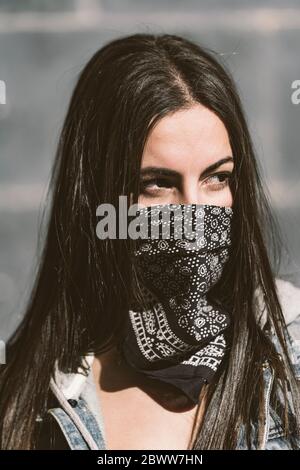 Portrait of beautiful young woman wearing neckerchief as mask Stock Photo