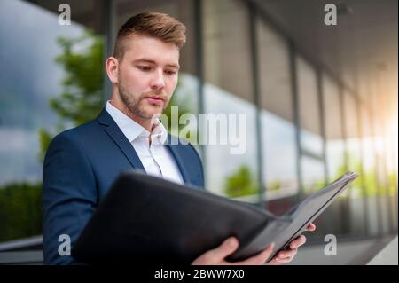 Portrait of a young businessman looking at folder in the city Stock Photo
