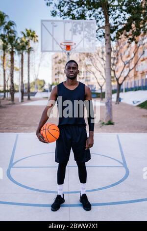 Young man holding basketball on basketball court Stock Photo