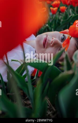 Portrait of woman lying between tulips Stock Photo