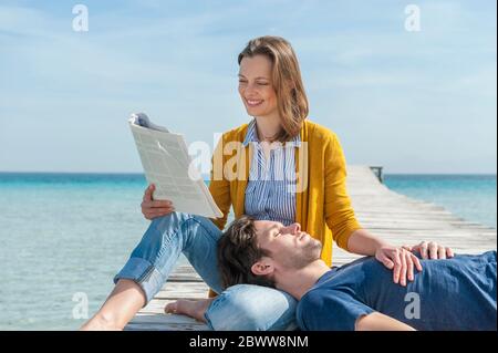 Portrait of happy woman relaxing with her partner on jetty, Mallorca, Spain Stock Photo