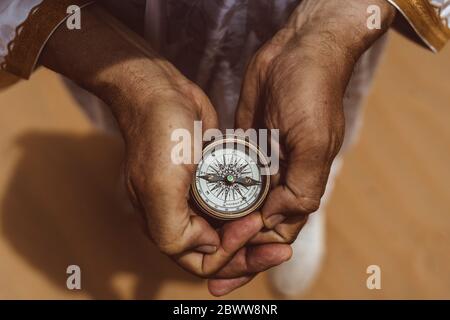 Hands holding compass in the desert, elevated view Stock Photo