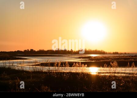 Amazing golden orange sunrise over the lake with the sun and a sunny walkway on the water Stock Photo