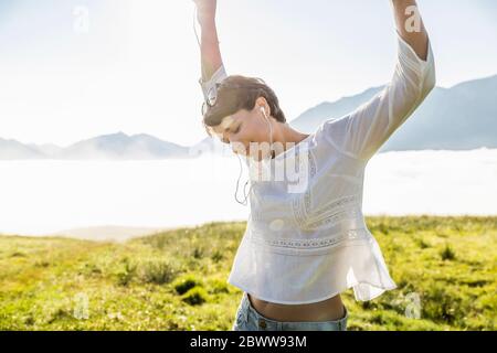 Happy woman listening to music on a meadow in the mountains, Achenkirch, Austria Stock Photo