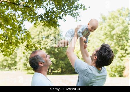 Senior man spending time with his adult son and his granddaughter in a park Stock Photo