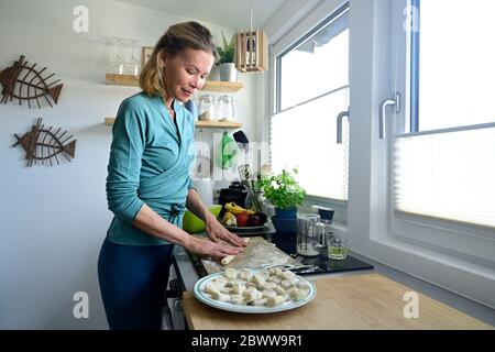 Woman preparing gnocchi in kitchen Stock Photo