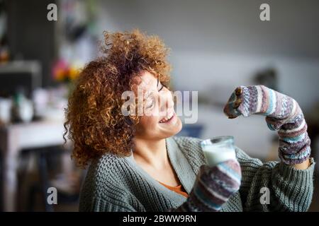 Happy woman playing with hand doll, holding glass of milk Stock Photo