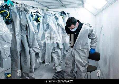 Healthcare worker wearing protective suit in locker room Stock Photo