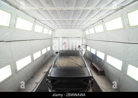 Body painter painting car in paint booth Stock Photo