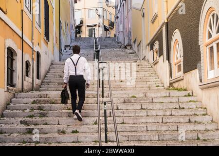 Rear view of young man walking up stairs in the old town, Lisbon, Portugal Stock Photo