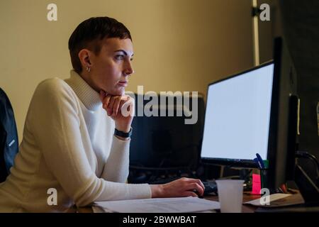 Redheaded young woman using computer at desk Stock Photo