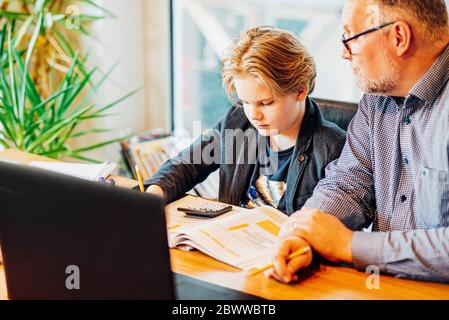 Father helping son doing homework at desk Stock Photo