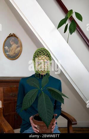 Portrait of teenage girl wearing crocheted green headdress holding potted avocado plant Stock Photo