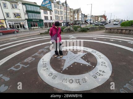 Elderly tourist reading quotes at the Eric Morecambe memorial in Morecambe, Lancashire, England Stock Photo