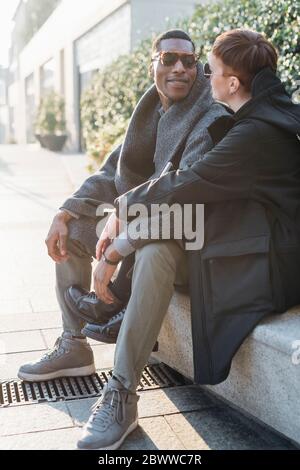 Young couple sitting on a wall in the city Stock Photo