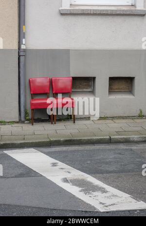 Two red old chairs standing side by side on pavement Stock Photo