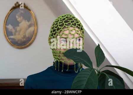 Portrait of teenage girl with avocado plant wearing crocheted green headdress Stock Photo