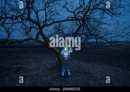 Spacewoman discovering a tree in the evening Stock Photo