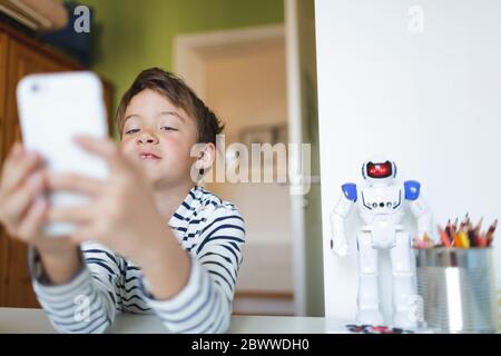Boy doing homeschooling and using smartphone at home Stock Photo