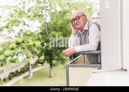 Portrait of smiling senior man standing on balcony Stock Photo