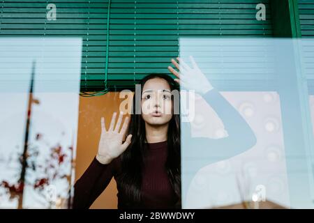 Portrait of young woman behind windowpane Stock Photo