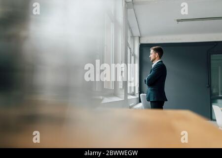 Portrait of brunette businessman looking out of window in office Stock Photo