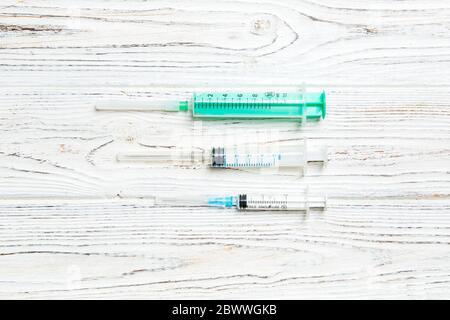 Top view of syringes of different sizes on wooden background. Medical equipment for injection concept with copy space. Stock Photo