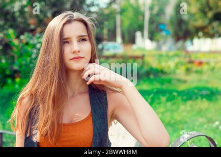 Woman thinking. Closeup portrait headshot face beautiful confident serious thoughtful young lady girl finger on chin isolated green park outdoor backg Stock Photo