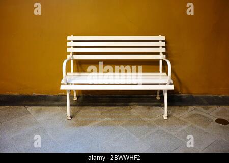 White Iron Bench with Brown Concrete Background. Stock Photo