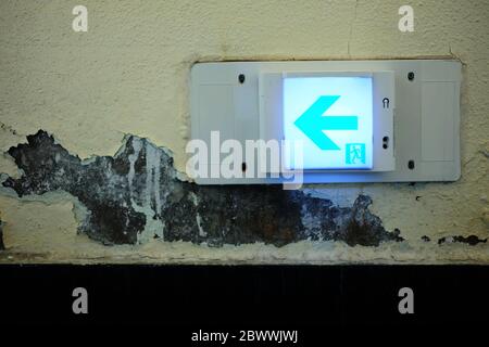 Emergency Exit Sign on Grunge Concrete Wall Background. Stock Photo