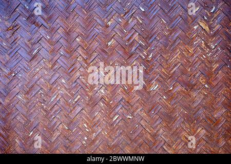 Red Peeling Paint on Wicker Bamboo Wall Background. Stock Photo