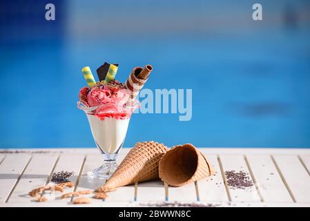 Front view of glass with strawberry ice cream on blur bokeh background with copy space. Raspberry sorbet with waffle chocolate cones on white table to Stock Photo