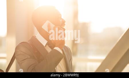Cheerful Businessman Talking On Phone Walking In Airport, Panorama Stock Photo