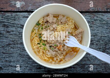 Top View of Instant Noodle with Pork Chops in the Cup on the Wooden Table Background. Stock Photo