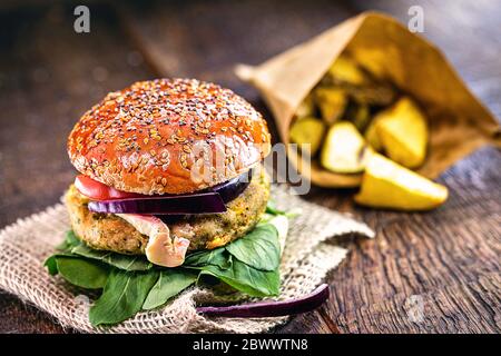 vegetarian burger with french fries in the background, gourmet food on rustic wooden table. Stock Photo