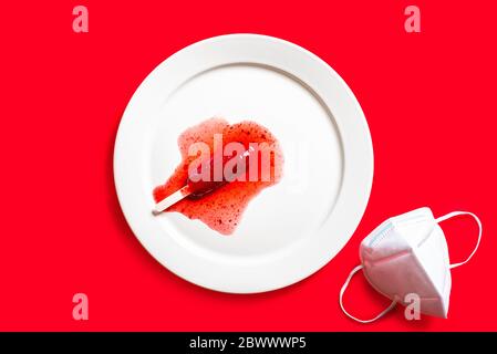Delicious defrosted strawberry popsicles and medical mask over red background Stock Photo