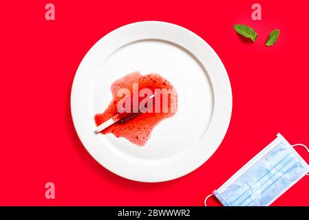 Delicious defrosted strawberry popsicles and medical mask over red background Stock Photo