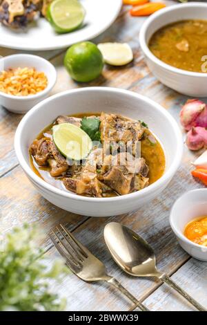 Oxtail soup served warm with sliced lime. Stock Photo