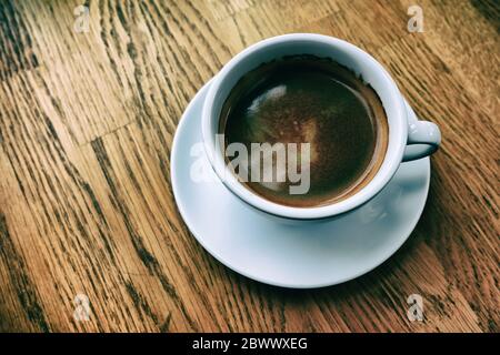White Cup of Black Coffee on the Wooden Table in Classic Tone. Stock Photo