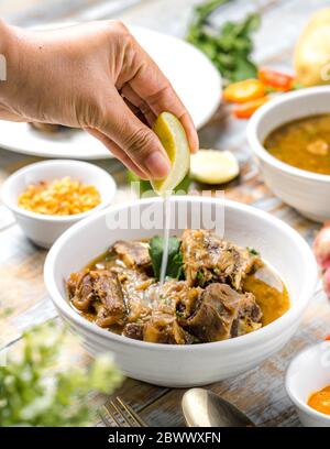 Oxtail soup served warm with sliced lime. Stock Photo