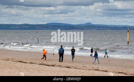 Portobello, Edinburgh, Scotland, UK. 3rd May 2020. A family entertain themselves on a fairly quiet beach after the crowds over the last few days during the mini heatwave, this afternoon is 13 degrees centigrade and thick cloud with a wind of 9km/h and gusts of 17km/h. Stock Photo