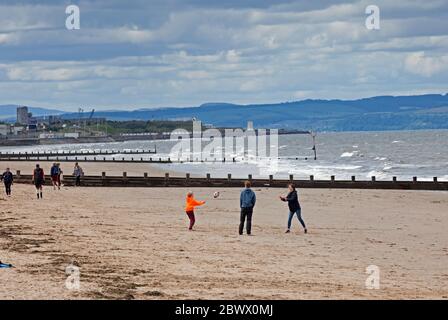 Portobello, Edinburgh, Scotland, UK. 3rd May 2020. A family entertain themselves on a fairly quiet beach after the crowds over the last few days during the mini heatwave, this afternoon is 13 degrees centigrade and thick cloud with a wind of 9km/h and gusts of 17km/h. Stock Photo