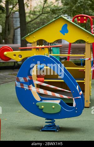 An empty playground without children with striped red and white warning tape, limitations quarantined for Covid19 coronavirus Stock Photo