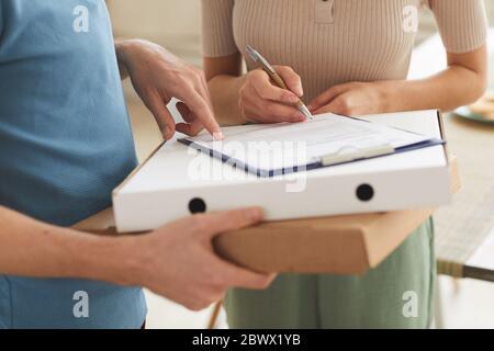 Close-up of woman signing for delivery and taking pizza from delivery man Stock Photo