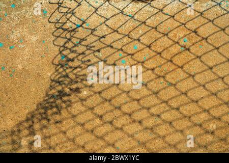 Broken Chain Fence Shadow on Concrete Ground. Stock Photo
